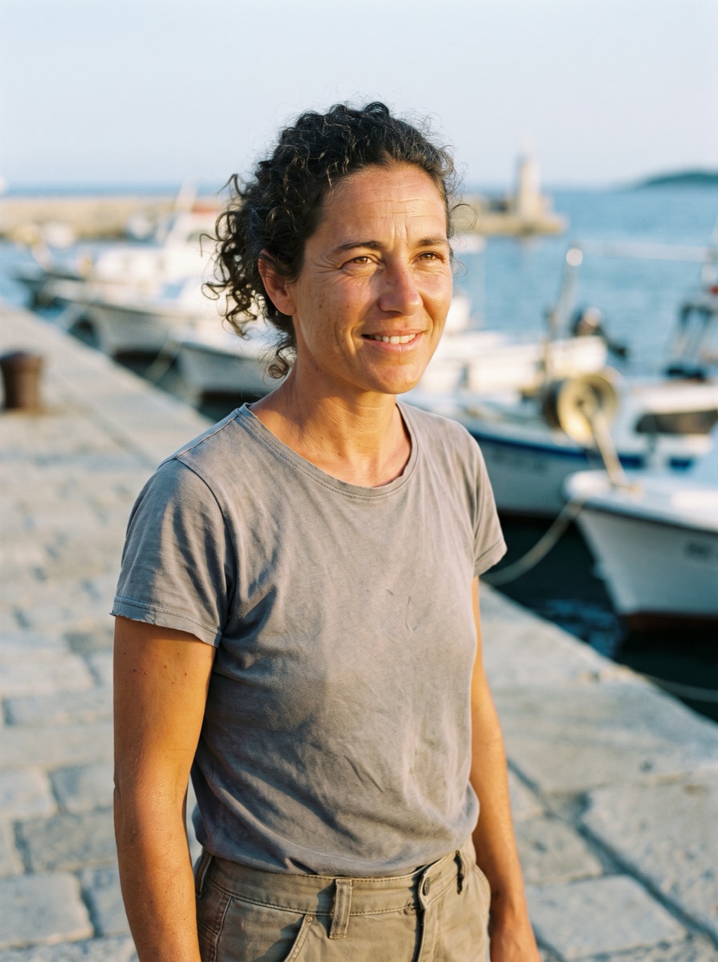 Elena Russo, a marine biologist with curly hair, smiling on the quay
